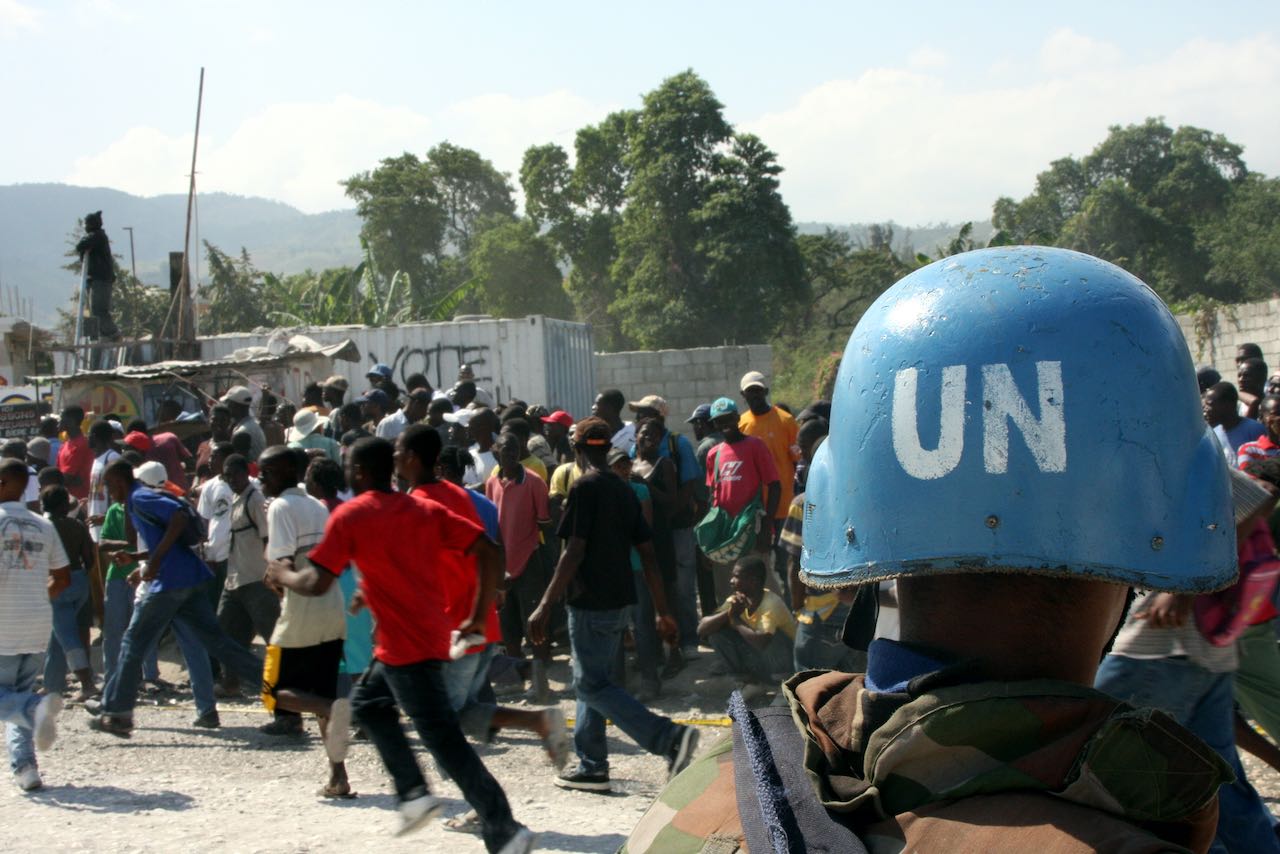 Un soldat sri-lankais attaché aux forces des Nations Unies en Haïti observe la foule qui se dirige vers le point de contrôle où les Haïtiens ont présenté un bon alimentaire pour recevoir des rations dans un point de distribution à Carrefour, en Haïti.