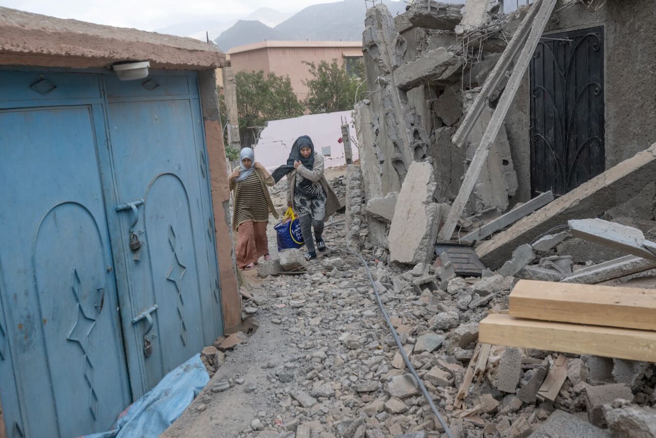 Des femmes passent devant les décombres d'une maison dans un village situé entre Marrakech et Taroudant dans la chaîne de montagnes de l'Atlas, le 17 septembre 2023, à la suite d'un puissant tremblement de terre.
